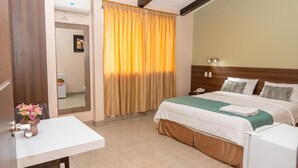 Quarto de hotel com cama, mesa de cabeceira e espelho.