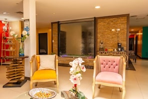 A lobby with two chairs, a glass table, and a decorative wall. - CRESPOTEL (Quevedo)