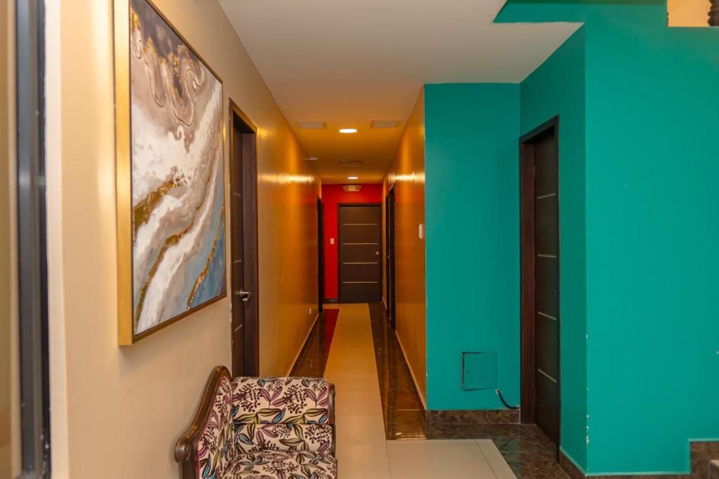 Un corridoio d'albergo con un divano a fantasia, un quadro astratto di grandi dimensioni e pareti color verde acqua.