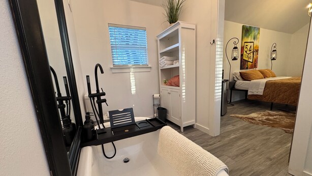 A bathroom with a bathtub, a towel rack, and a window with blinds. - Cabin 1 of 4 comfortably nestled in a country setting with amazing sunset view (Weatherford)