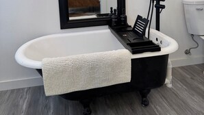 A bathroom with a freestanding bathtub, a black sink, and a large mirror. - Cabin 1 of 4 comfortably nestled in a country setting with amazing sunset view (Weatherford)
