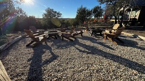 A gravel patio with wooden Adirondack chairs and a circular fire pit. - Cabin 1 of 4 comfortably nestled in a country setting with amazing sunset view (Weatherford)