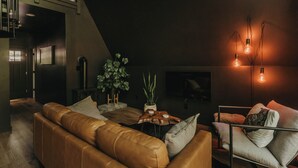 A modern living room with a leather sofa, a coffee table, and a floor lamp. - Charming 2-bedroom A Frame cabin in Red River Gorge - The Raven (Rogers)
