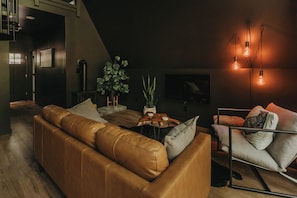 Ett modernt vardagsrum med en soffa i läder, ett soffbord och en golvlampa.