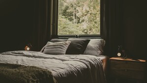 A bedroom with a large window, a bed with pillows, and two bedside lamps. - Charming 2-bedroom A Frame cabin in Red River Gorge - The Raven (Rogers)