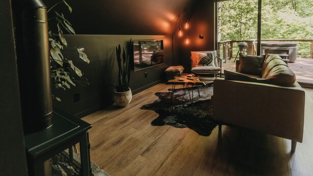 A modern living room with a fireplace, a large window, and a cozy seating area. - Charming 2-bedroom A Frame cabin in Red River Gorge - The Raven (Rogers)