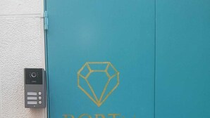 A teal door with a security keypad and a diamond-shaped logo with the text "PORTA SERENO". - Portu Sereno Pearl - Ground floor (Setúbal)