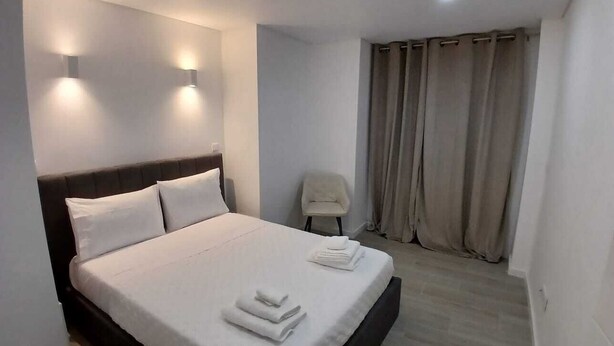 A neatly made bed with white linens and towels, a headboard, and two wall-mounted lights. - Portu Sereno Pearl - Ground floor (Setúbal)