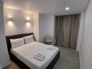 A neatly made bed with white linens and towels, a headboard, and two wall-mounted lights. - Portu Sereno Pearl - Ground floor (Setúbal)