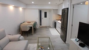 A modern apartment with a living room, dining area, kitchen, and a TV on a stand. - Portu Sereno Pearl - Ground floor (Setúbal)
