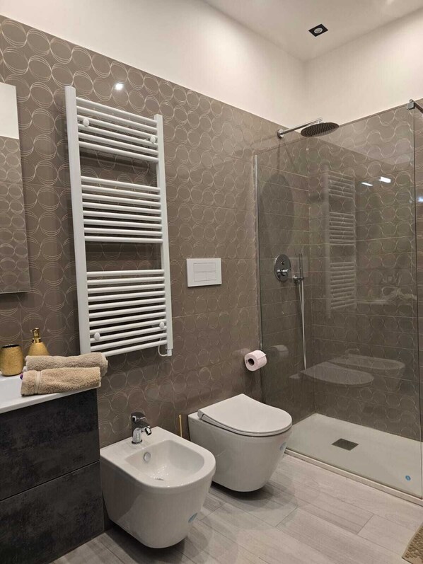 A modern bathroom with a bidet, toilet, and glass shower enclosure.