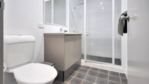 A modern bathroom with a toilet, sink, and shower. - Substantial Studio 1x1 (Port Hedland)
