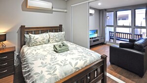 A hotel room with a bed, a desk, a TV, and a balcony with a view of the city. - Substantial Studio 1x1 (Port Hedland)