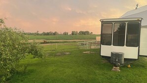A grassy area with a white building, a fenced field, and a tractor. - Yahweh Horse Retreat (Long Prairie)