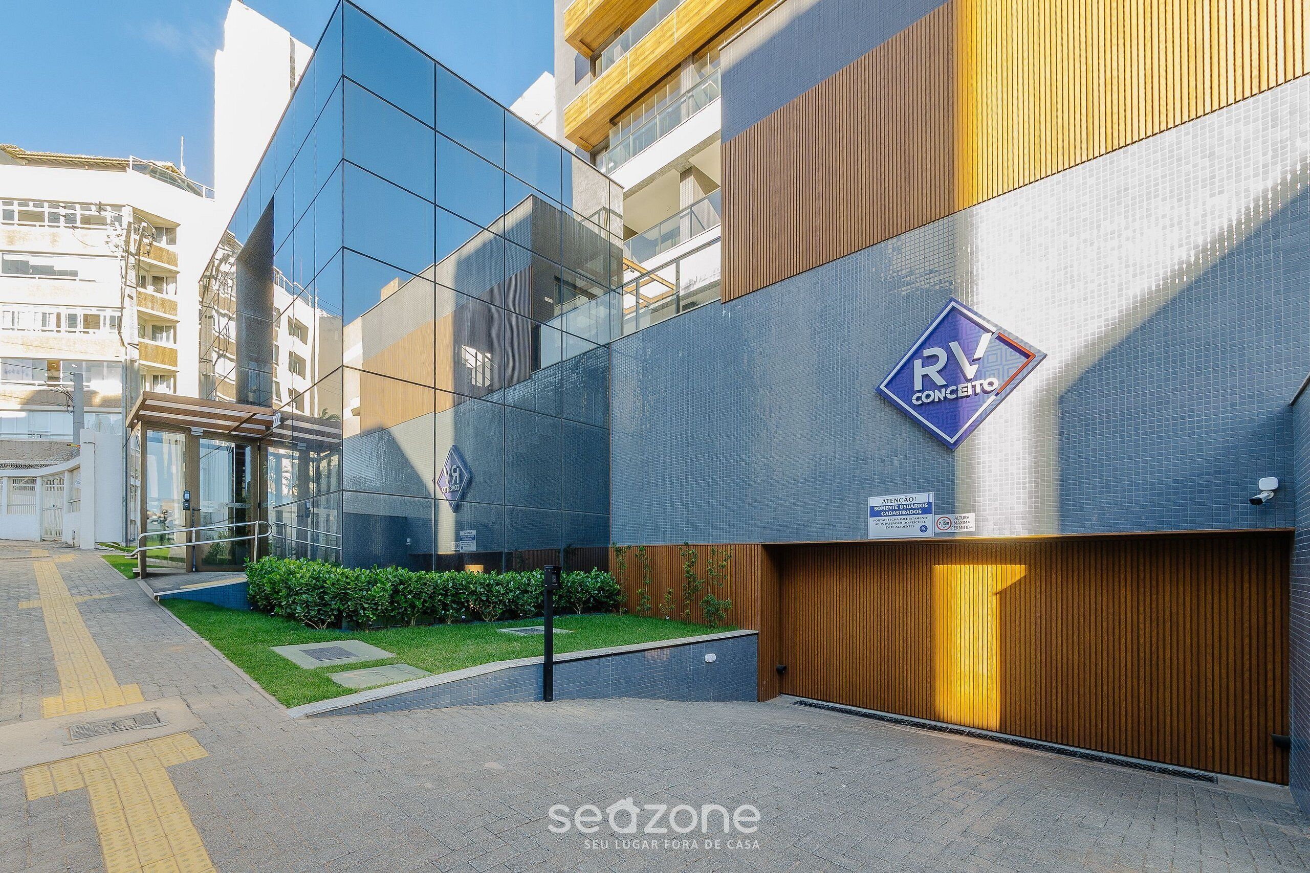 Um edifício moderno com fachada de vidro, parte em painel de madeira e uma placa indicando RV Concessio.