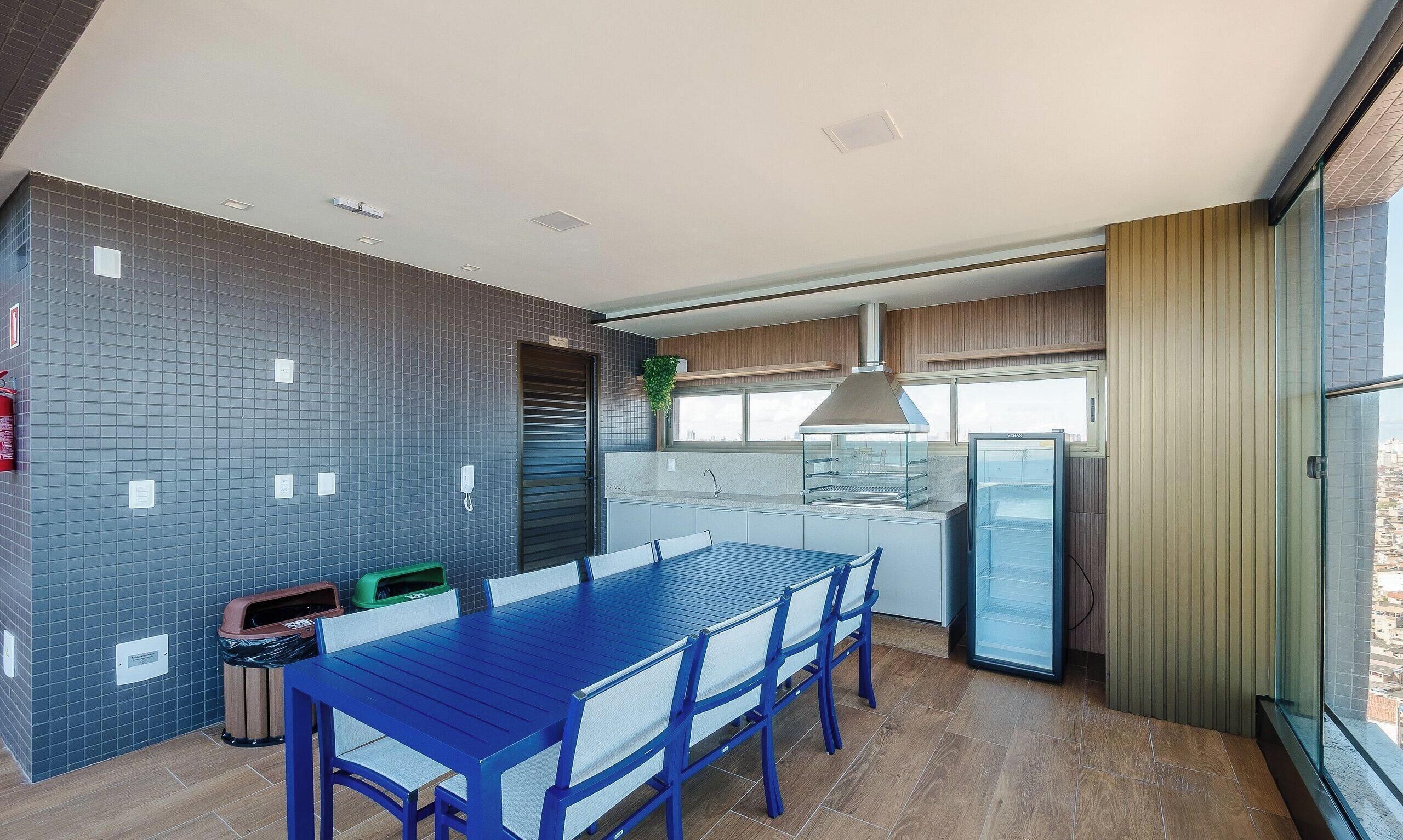 Una cocina moderna con una mesa y sillas de comedor azules, un horno empotrado y un ventanal amplio.