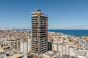 Un immeuble imposant doté de balcons, une enseigne indiquant « 1/4 A STUDIO VISITE DECORADOS », et une vue sur le paysage urbain de la côte.