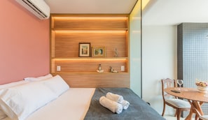 A hotel room with a bed, a small table with a vase, and a wall with shelves displaying decorative items. - Apartments in a Building With a Pool 800m From the Beach in Salvador - EDF (Salvador)