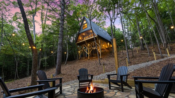 A cabin with a fire pit and Adirondack chairs in a forest setting. - Creekside • Sauna • Hot Tub • Fire Pit • 15 min to Town (Morganton)