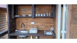 Una cucina compatta con lavello, scolapiatti e scaffali portaoggetti.