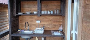 A compact kitchen with a sink, a dish rack, and shelves above for storage.