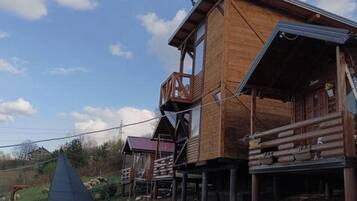 Une cabane en bois dotée d’un balcon, d’un petit porche et d’une fenêtre bien visible.
