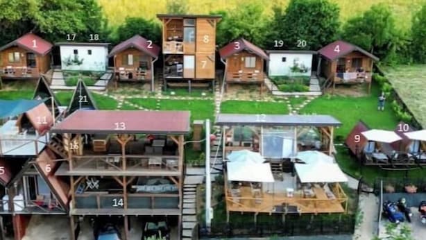 Un gruppo di casette in legno, numerate da 1 a 20, disposte a semicerchio attorno a uno spazio aperto centrale.