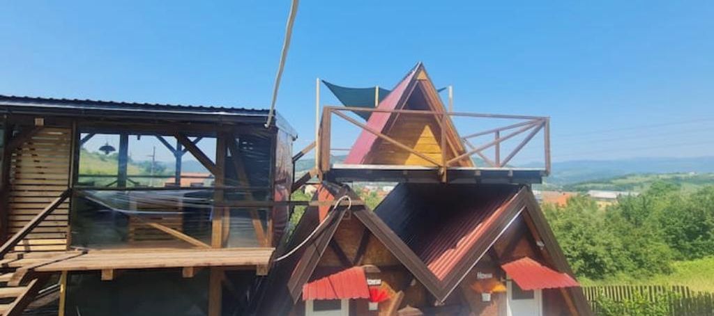 Une cabane en bois dotée d’une toiture triangulaire et d’une terrasse en bois.