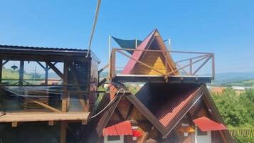 Une cabane en bois dotée d’une toiture triangulaire et d’une terrasse en bois.