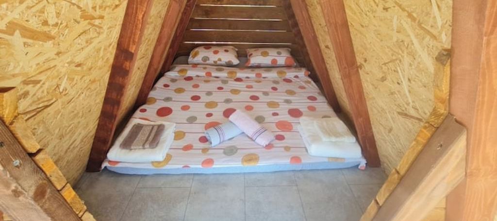 A small, cozy attic bedroom with a sloped ceiling and wooden walls.