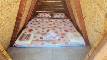 A small, cozy attic bedroom with a sloped ceiling and wooden walls.