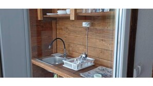 A compact kitchen with a wooden backsplash, a single sink, and a dish rack. - White Bosnian pyramid glamping (Visoko)
