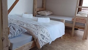 A room with two wooden bunk beds, one with a white bedspread and pillows, and the other with a grey bedspread and pillows. - White Bosnian pyramid glamping (Visoko)
