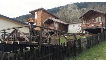 Een rij houten blokhutten met een houten terras en een hek er voor.