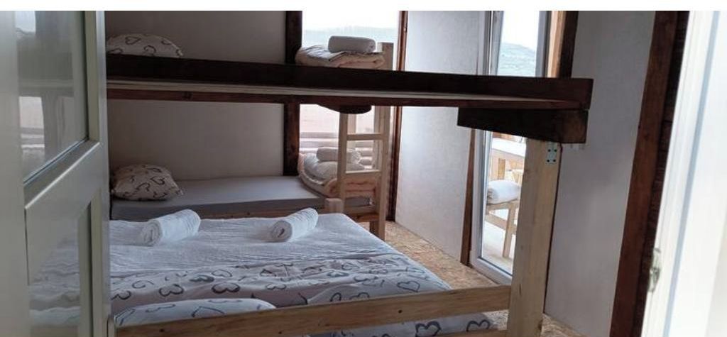 Un lit superposé avec une structure en bois et un lit inférieur doté de draps à motifs.