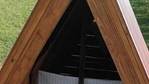 A wooden tent-like structure with a triangular roof and a white curtain. - Dragon Tent Bos pyramid glamping (Visoko)