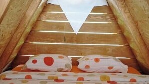 A small, cozy attic bedroom with a sloped ceiling, wooden beams, and a bed with polka dot bedding. - Dragon Tent Bos pyramid glamping (Visoko)