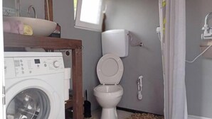 A compact bathroom with a washing machine, toilet, and shower area. - Dragon Tent Bos pyramid glamping (Visoko)