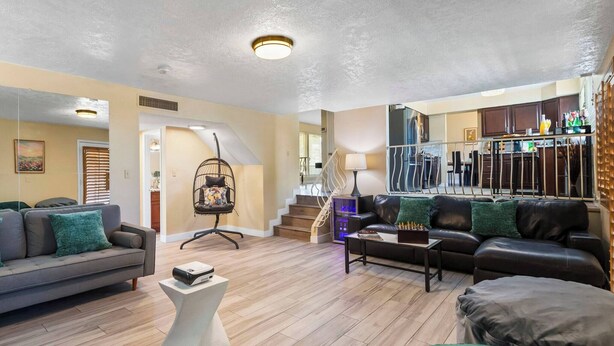 Een moderne woonkamer met een bank, salontafel en een trap die leidt naar een keuken.