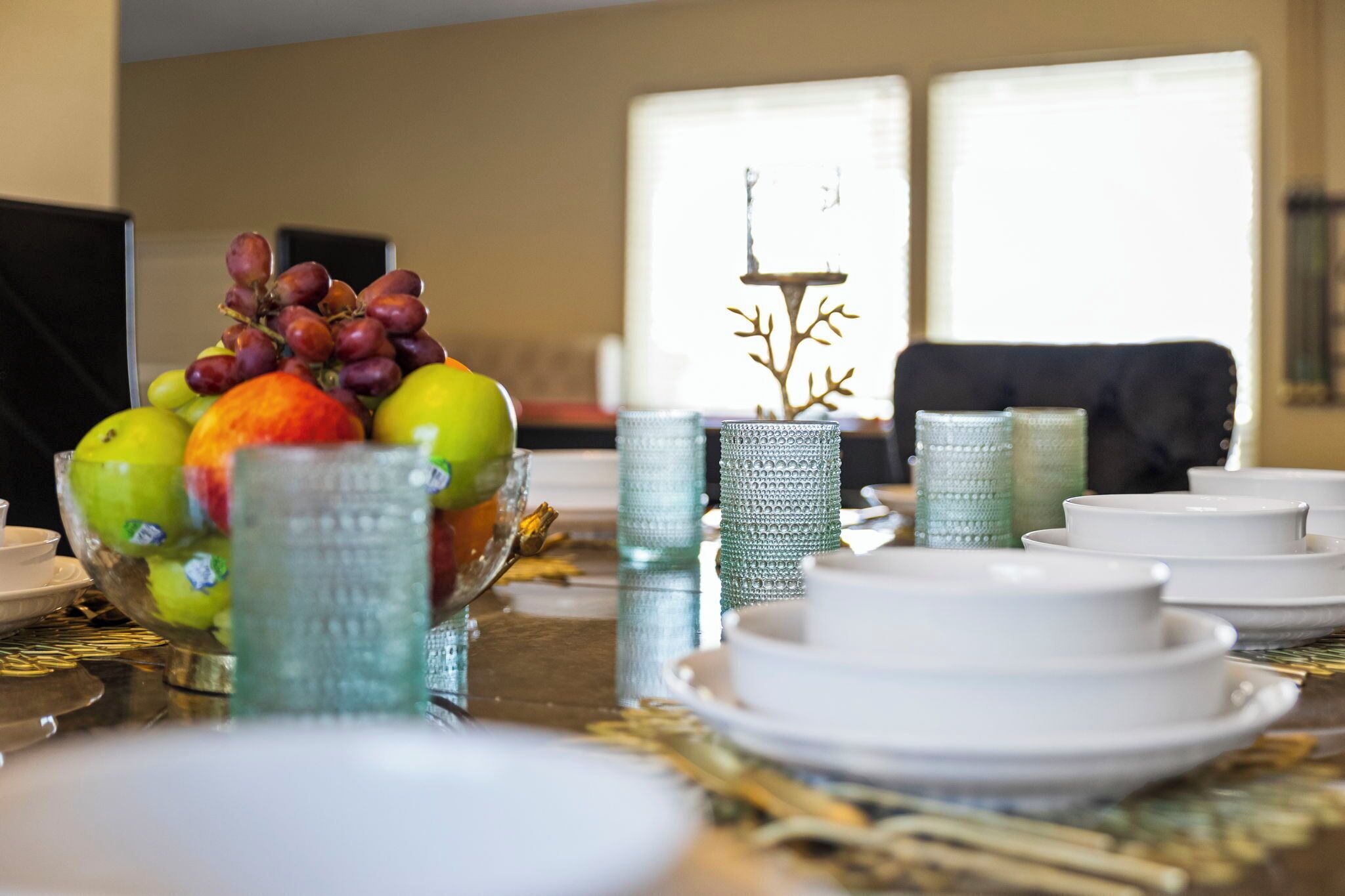 Uma mesa de jantar posta com pratos, tigelas e objetos decorativos.