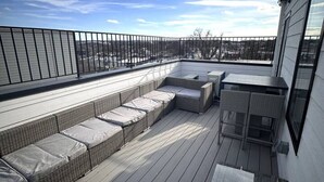 A rooftop deck with a long bench and a small table. - DC Penthouse: Rooftop+ Views+ 3BD+ Private Parking (Washington)