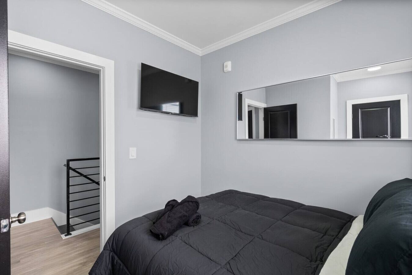Een slaapkamer met een bed, een grote spiegel en een deur naar een balkon.