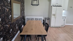 Een eetruimte met een houten tafel en stoelen, een zwart-wit patroonkast en een witte koelkast.