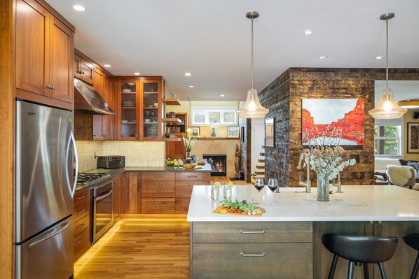 A modern kitchen with wooden cabinets, stainless steel appliances, and a central island with seating.