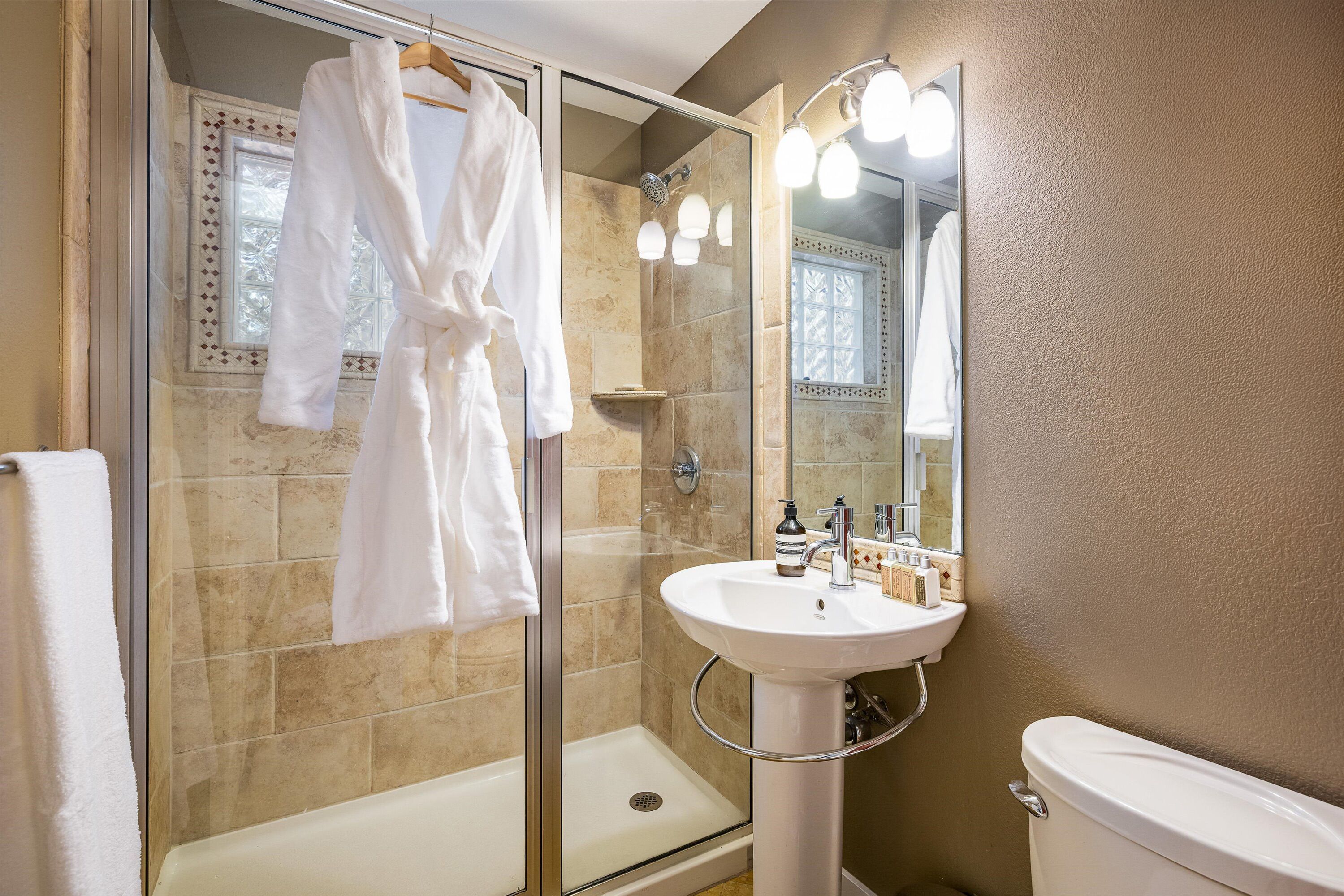 Un bagno con doccia vetrata, un lavandino bianco e un water.