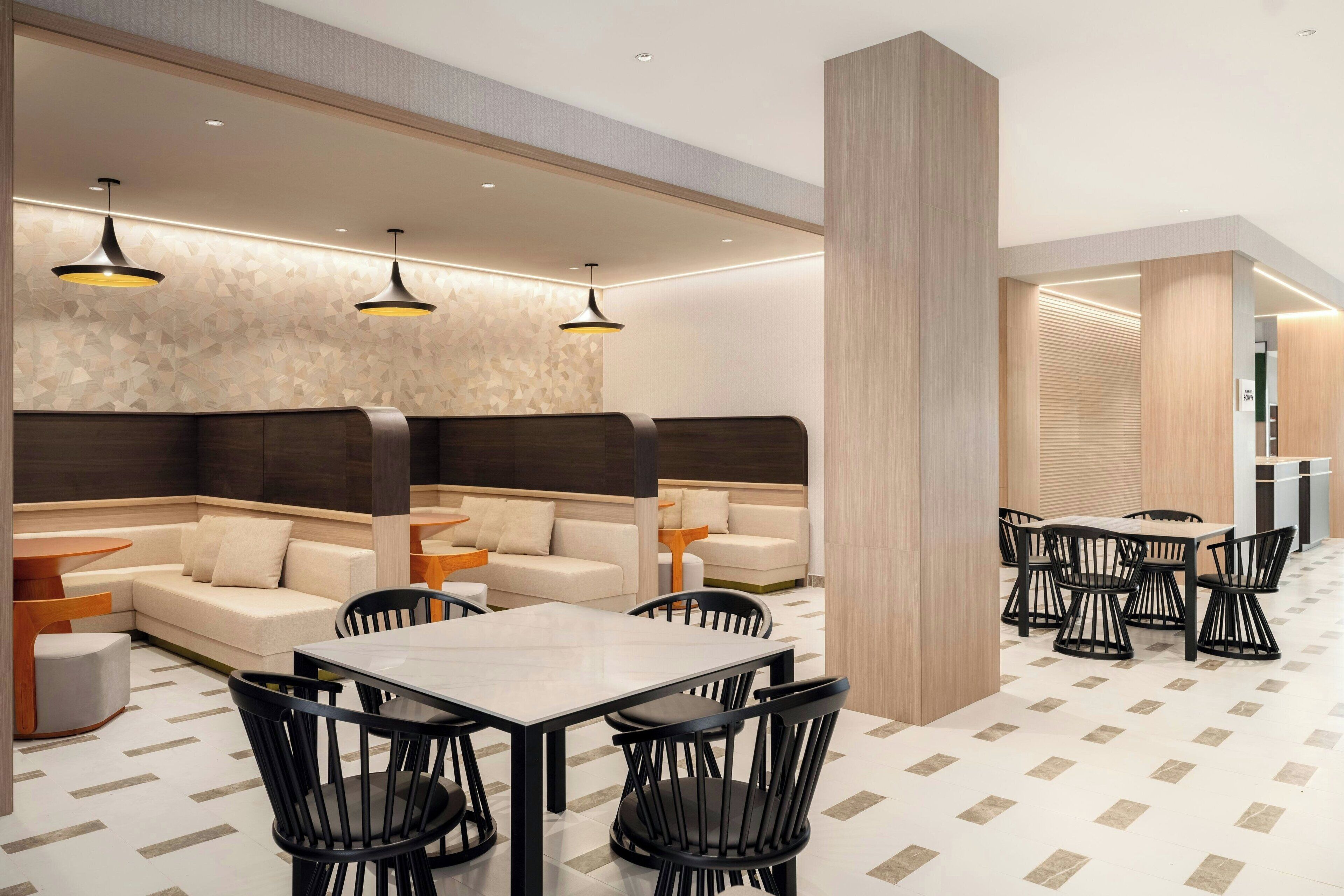 A modern restaurant with a central dining area, booths, and a bar area.