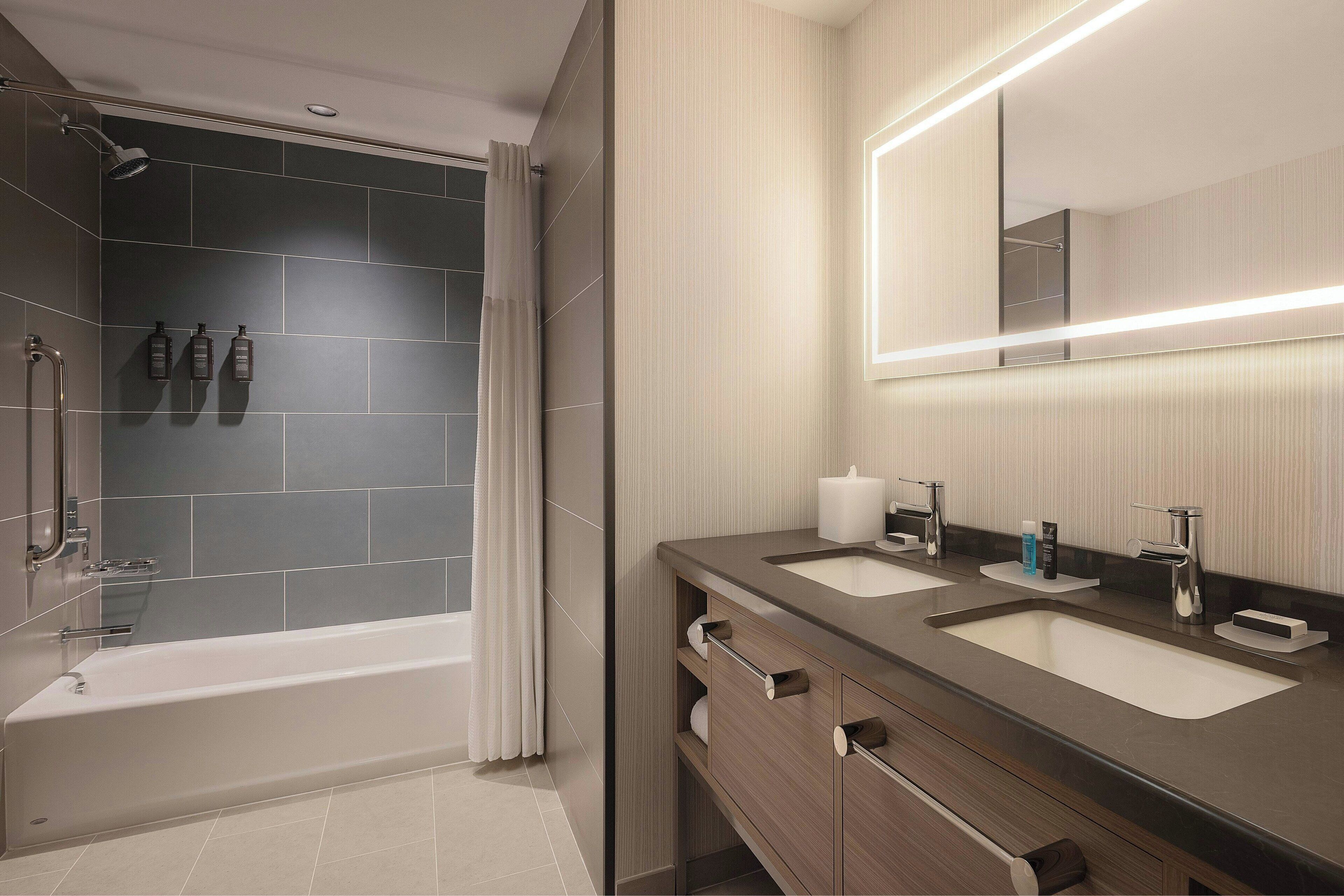 Un baño moderno con bañera, dos lavamanos y zona de ducha.