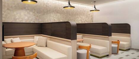 A modern lounge area with a sofa, a round table, and a small stool.