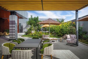 Un área de patio al aire libre con una mesa de comedor, sillas y un sillón colgante.