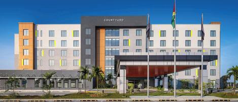 Un hotel Courtyard by Marriott con fachada moderna, varios pisos y un estacionamiento frente a él.